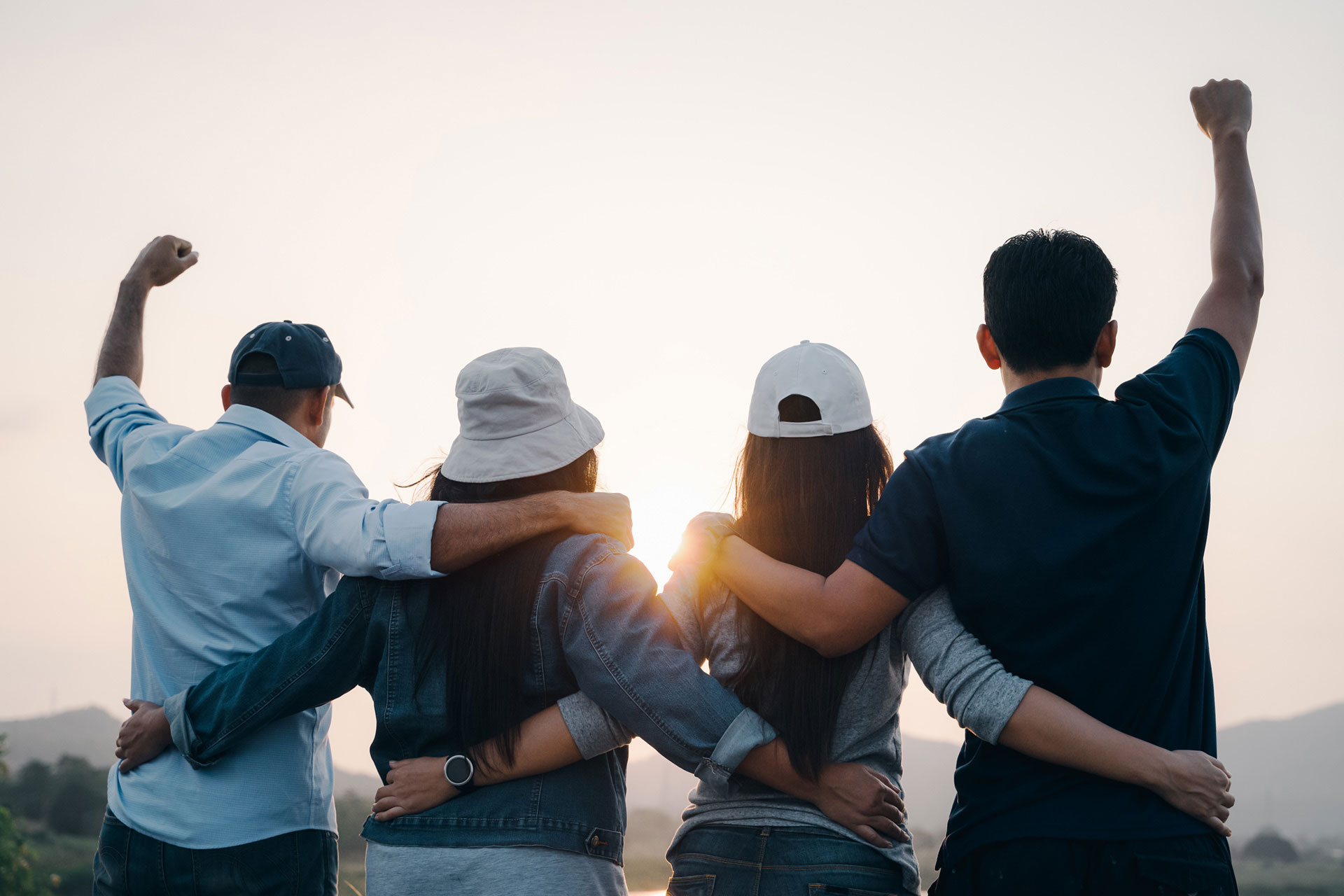 group-people-with-raised-arms-looking-sunrise-mountain-background